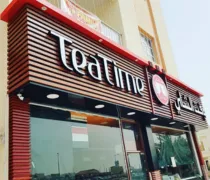 A cafe storefront featuring a wooden facade with 'Teatime' prominently displayed and large glass windows