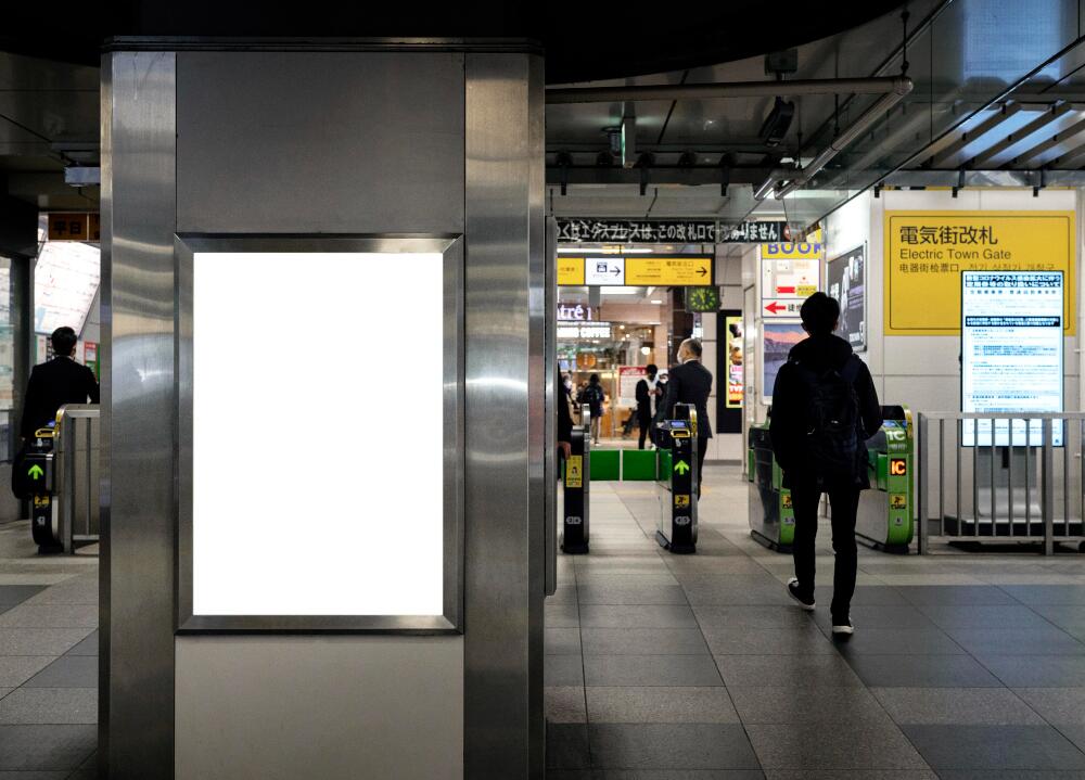 Digital screens advertising in metro station entrance with commuters